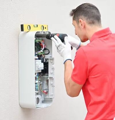 Photo d'un artisan qui installe une borne de recharge pour voiture électrique à domicile