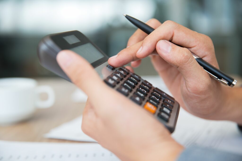 Photo d'un artisan avec une calculatrice dans les mains réalisant un devis pour l'installation d'une borne de recharge.